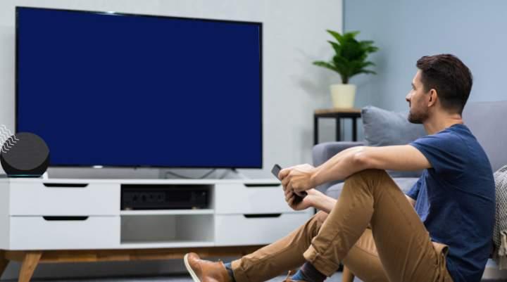 Man watching the TV which is near his smart speaker device